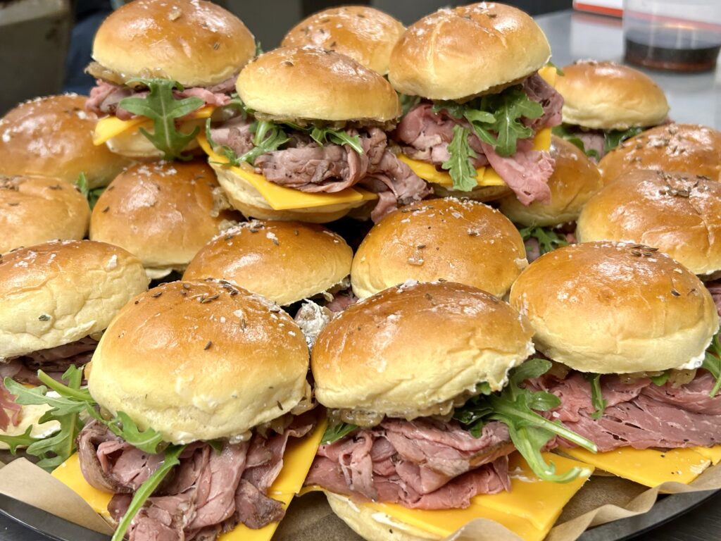 Shaved beef sliders with melted cheese on brioche buns from Happy Belly catering