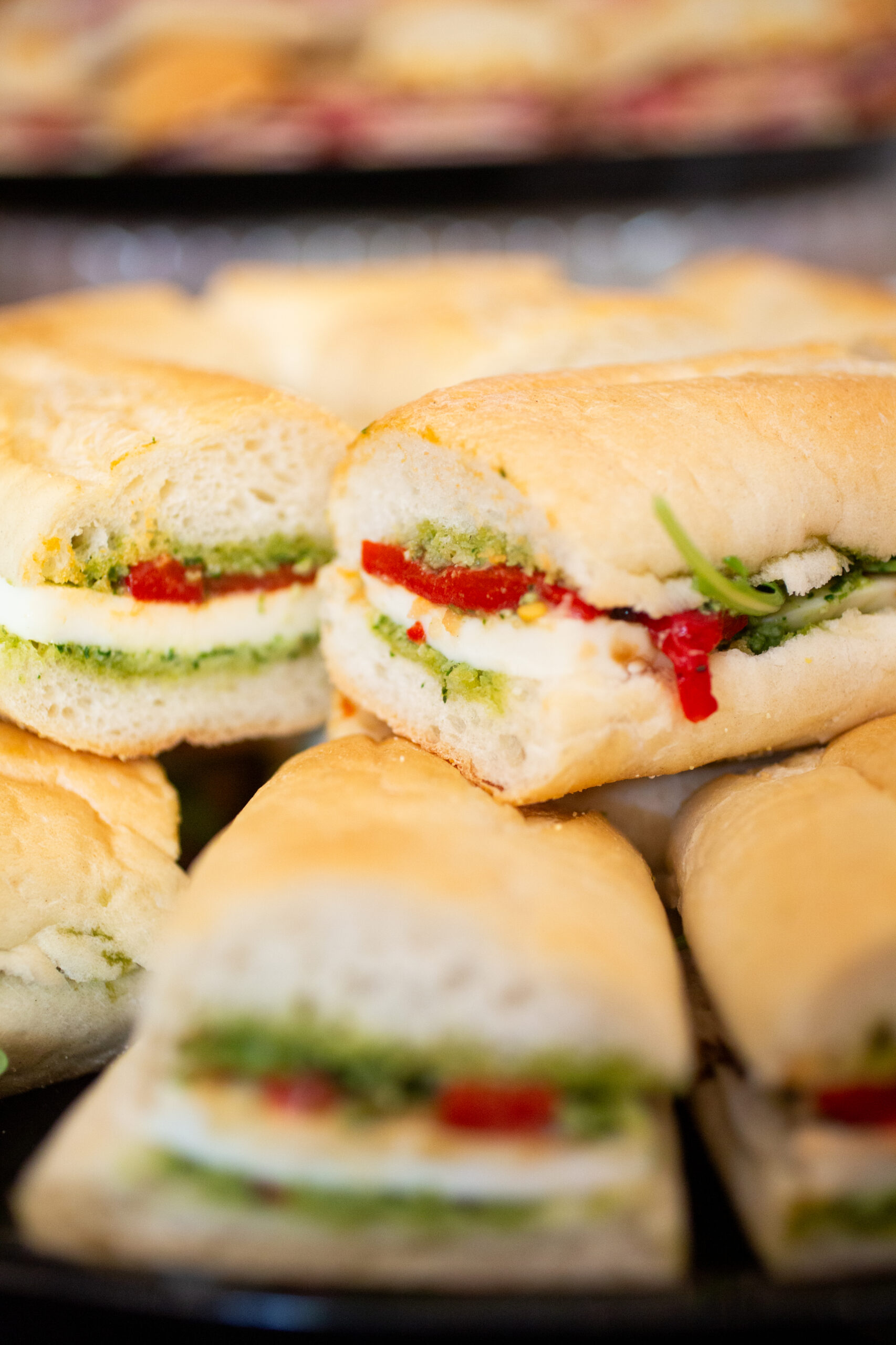 Pesto mozzarella slider with roasted red peppers on a fresh-baked baguette from Happy Belly Catering
